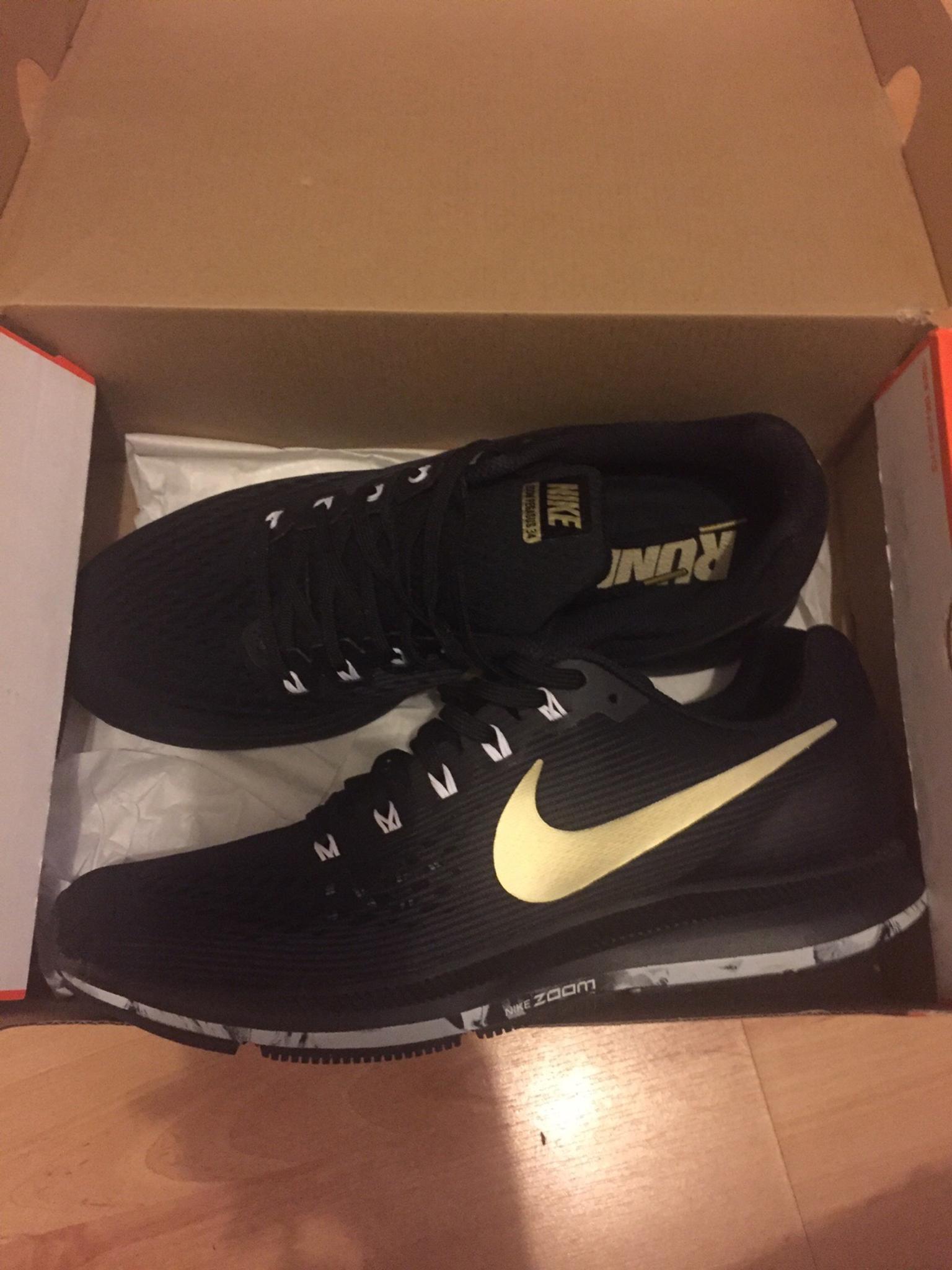 black nike trainers with gold tick